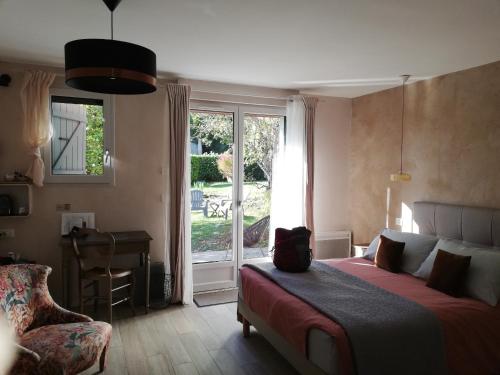 a bedroom with a bed and a window and a desk at Les Perluètes - Chambres d'hôtes in Carennac