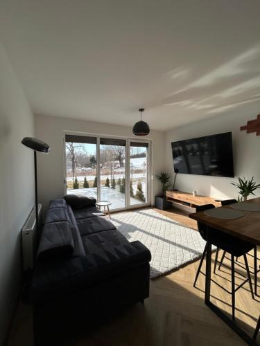 a living room with a black couch and a table at Apartament Bond in Szczawno-Zdrój