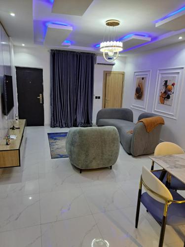 a living room with couches and chairs and a tv at Diolux Comfy Apartments in Sangotedo