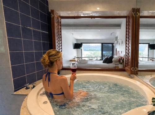 a woman in a bath tub holding a glass of wine at BlueWater Penthouse GuestSuite 3 in Newport