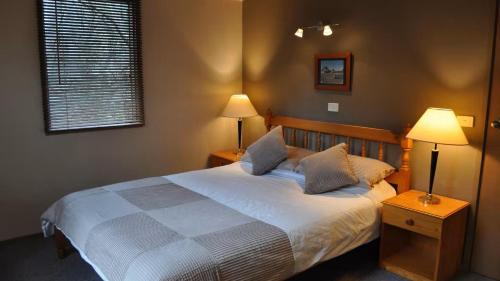 a bedroom with a bed with two lamps and a window at Highlander in Dinner Plain