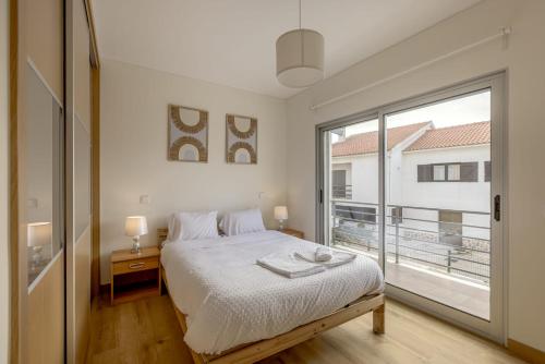 a bedroom with a bed and a large window at Beachside Villa with Private Garden in Aldeia do Meco