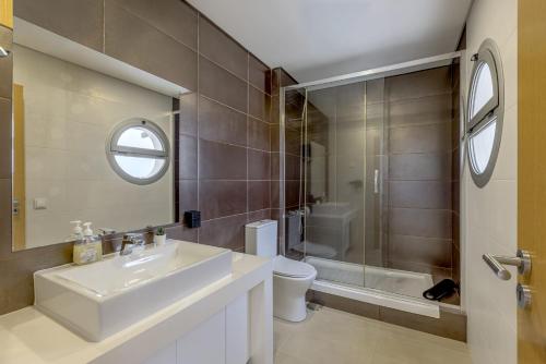 a bathroom with a sink and a toilet and a mirror at Beachside Villa with Private Garden in Aldeia do Meco