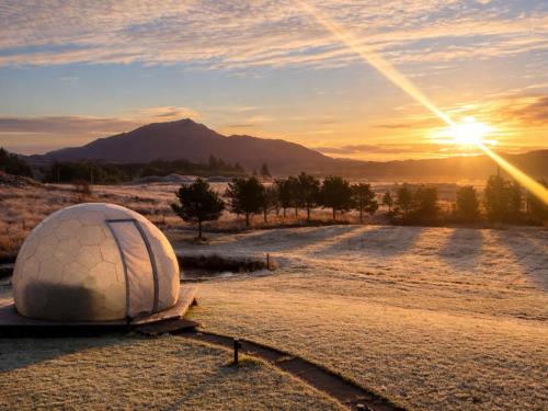a dome tent in a field with the sunset at Mingarry Park in Acharacle