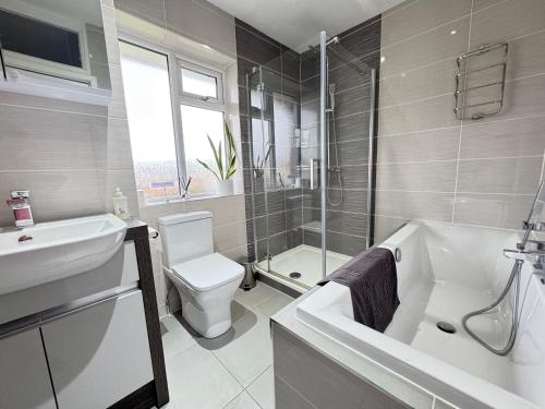 a bathroom with a toilet and a tub and a sink at Very Spacious 4 Bedroom house with large garden in Leamington Spa