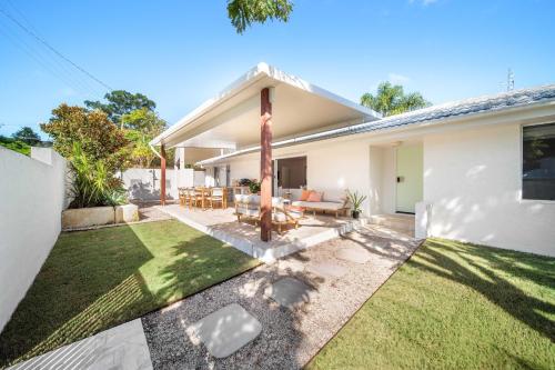 a backyard of a white house with a lawn at Solara Escape Mooloolaba - Luxe Pet-Friendly Home in Alexandra Headland