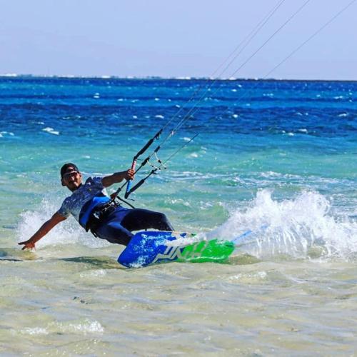 a man on a surfboard in the water at Dagal Camp - دجل كامب in Sharm El Sheikh