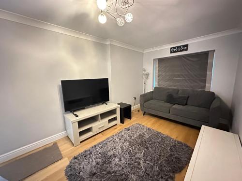 a living room with a couch and a flat screen tv at Contractors Home - 4 Bedroom Long Stays Welcome - Barnsley in Shafton
