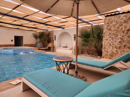 استراحة ريف حتا في حتا: مسبح به كراسي ومظلة بجوار المسبح