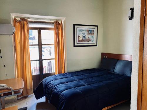 a bedroom with a blue bed and a window at Hotel Santo Domingo in Zacatecas