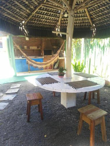 a patio with a table and benches and a hammock at Edícula 2 quartos frente mar in Ilhéus
