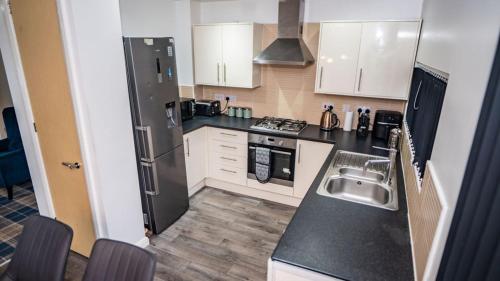 a kitchen with a sink and a black refrigerator at Etihad Coop Arena City Centre Stay in Manchester