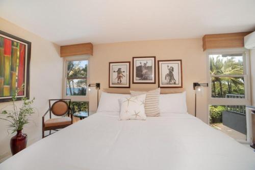 a large white bed in a room with windows at Nani Kai Hale 308 in Kihei