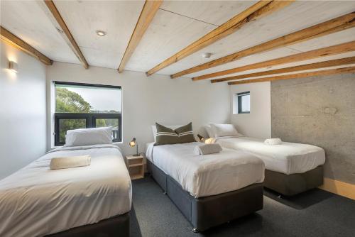 two beds in a room with white walls and wooden ceilings at Nelse Lodge in Falls Creek