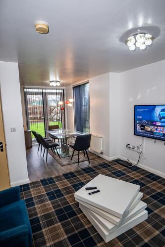 a living room with a table and chairs and a tv at Etihad Coop Arena City Centre Stay in Manchester