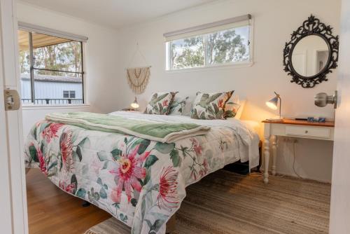a bedroom with a bed with a floral bedspread at Clarendon Cottage, near Lowood , Fernvale, right on the BVRT in Clarendon