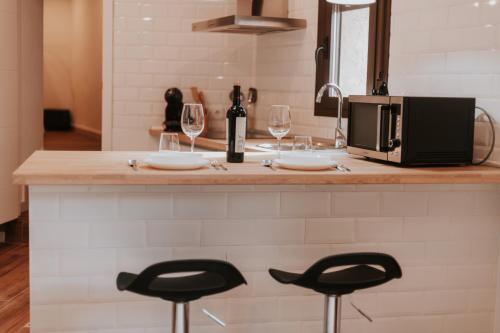 a kitchen with a counter with two chairs and a microwave at Apartamentos Cañón de la Rinconada in Trujillo