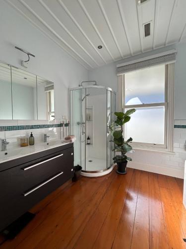 a large bathroom with a shower and a wooden floor at Auckland City Villa in Auckland