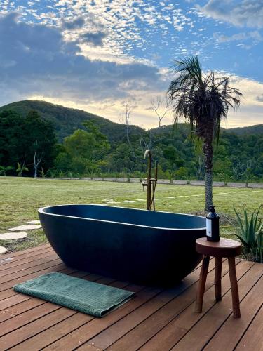 a blue tub sitting on a wooden deck with a palm tree at Private Treehouse Digital Detox Retreat with Fire Pit and Outdoor Bath in Kin Kin