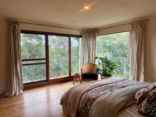 a bedroom with a large bed and a large window at Private Treehouse Digital Detox Retreat with Fire Pit and Outdoor Bath in Kin Kin