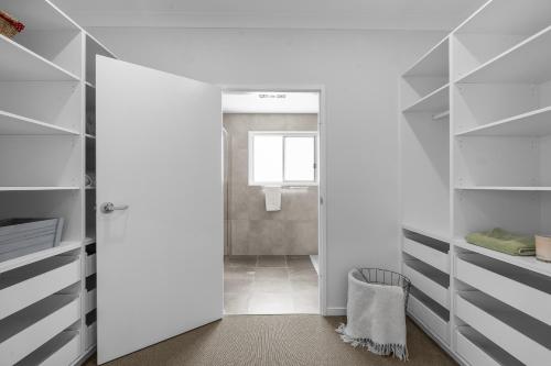 a bathroom with a door leading into a closet at Misons Guesthouse in Mollymook