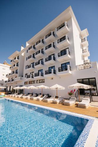 ein Hotel mit einem Schwimmbad vor einem Gebäude in der Unterkunft Chimaera Hotel in Himarë