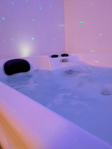 a purple room with a tub filled with water at Suite Évasion Spa - Tiny House in Vernouillet