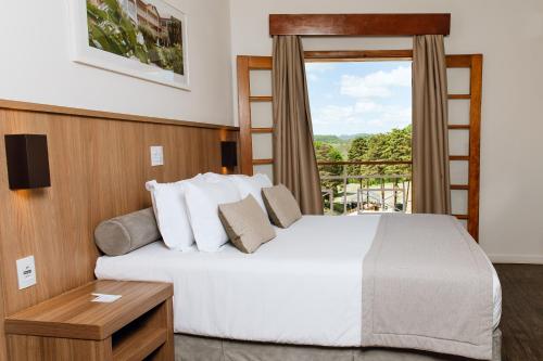 a hotel room with a bed and a window at Hotel Monreale Resort in Poços de Caldas