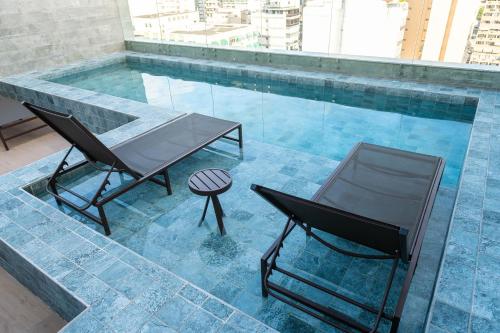 two chairs and a table next to a swimming pool at Loft moderno e aconchegante no coração de Icaraí in Niterói
