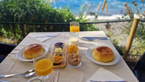 a table with plates of food and glasses of orange juice at Faja dos Padres in Ribeira Brava