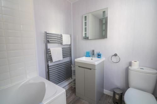 a white bathroom with a toilet sink and a mirror at Crew House in Dartmouth