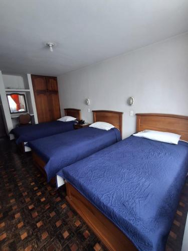 two beds in a hotel room with blue sheets at Hotel Rio Mayo in Pasto