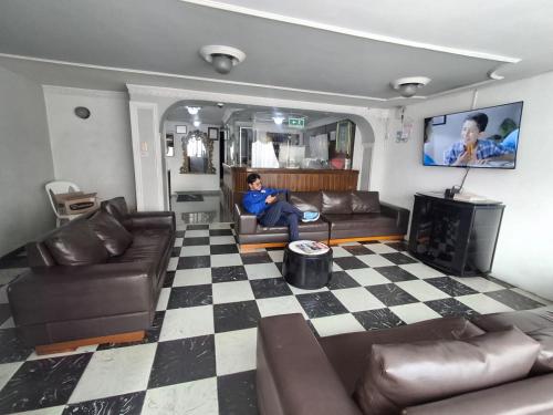 a man sitting on a couch in a living room at Hotel Rio Mayo in Pasto
