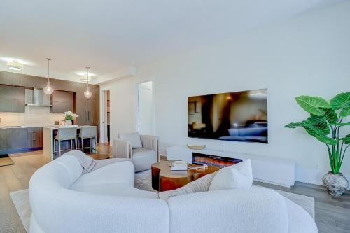 a living room with two white couches and a kitchen at Skyline Penthouse in Toronto