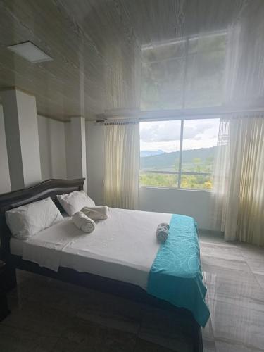 a bed in a bedroom with a large window at Hotel Puerto azul in Chitaraque