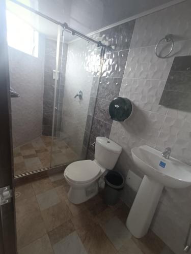 a bathroom with a toilet and a shower and a sink at Hotel Puerto azul in Chitaraque