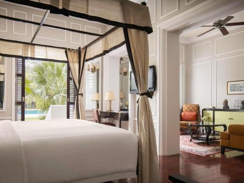 a bedroom with a bed and a living room at Raffles Grand Hotel d'Angkor in Siem Reap