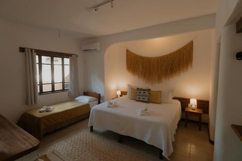 a bedroom with two beds and a window at Pousada Erva Doce in Arraial d'Ajuda