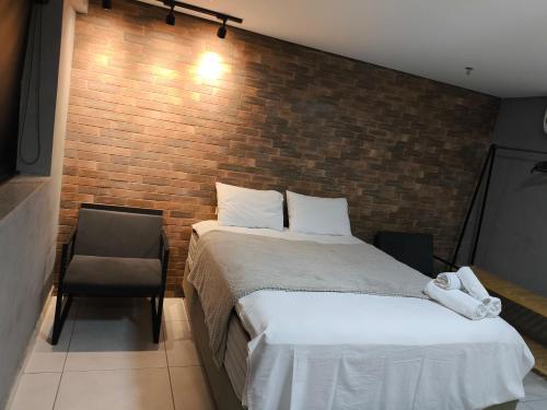 a bedroom with a bed and a brick wall at Flat Palmas Vivence Suítes in Palmas