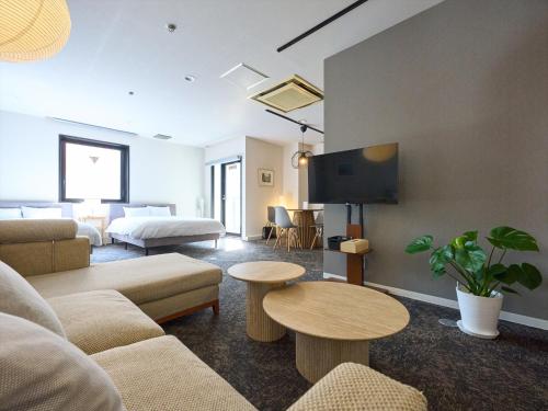 a living room with a couch and a tv at Retrospect Stay Kannai in Yokohama