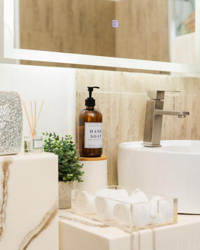 a bathroom with a sink and a bottle of soap at Ahra Suites First Floor with ocean view in Kingstown