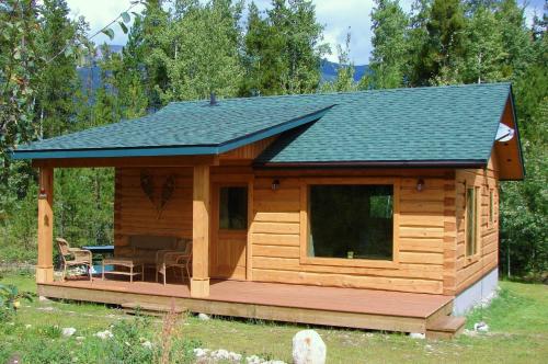 een blokhut met een terras en een dak bij Mica Mountain Lodge & Log Cabins in Tete Jaune Cache