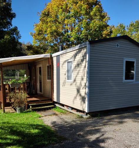 a tiny house with a porch and a shed at Monpetitmobilhome in Ascarat