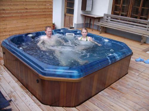 two people in a hot tub in a deck at Gästehaus Alpenblick Wildstrubel in Sankt Stephan
