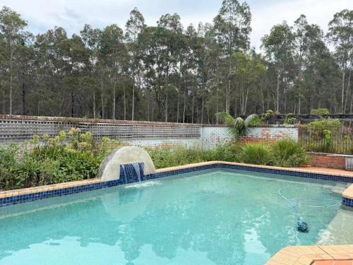 a swimming pool with a water fountain in a yard at Spacious Queen and Single Farmhouse Room in Worragee