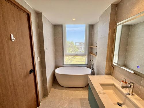a bathroom with a tub and a sink and a window at Aurora Golf Villa in Bình Sum