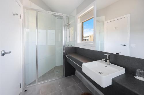 a white bathroom with a sink and a shower at Waves Luxury Suites & Port Central Apartments in Port Campbell