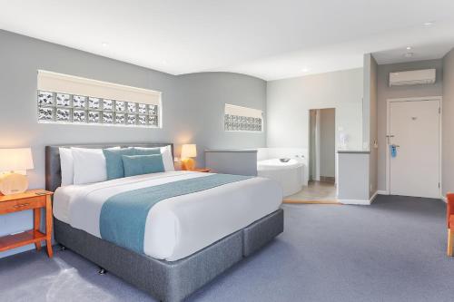 a bedroom with a large bed and a bathroom at Waves Luxury Suites in Port Campbell