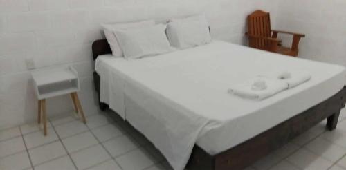 ein Schlafzimmer mit einem großen weißen Bett und einem Stuhl in der Unterkunft Uncle Ben's in Apia