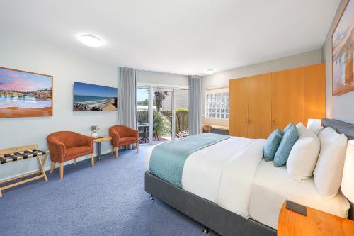 a bedroom with a large bed and a desk and chairs at Waves Luxury Suites & Port Central Apartments in Port Campbell